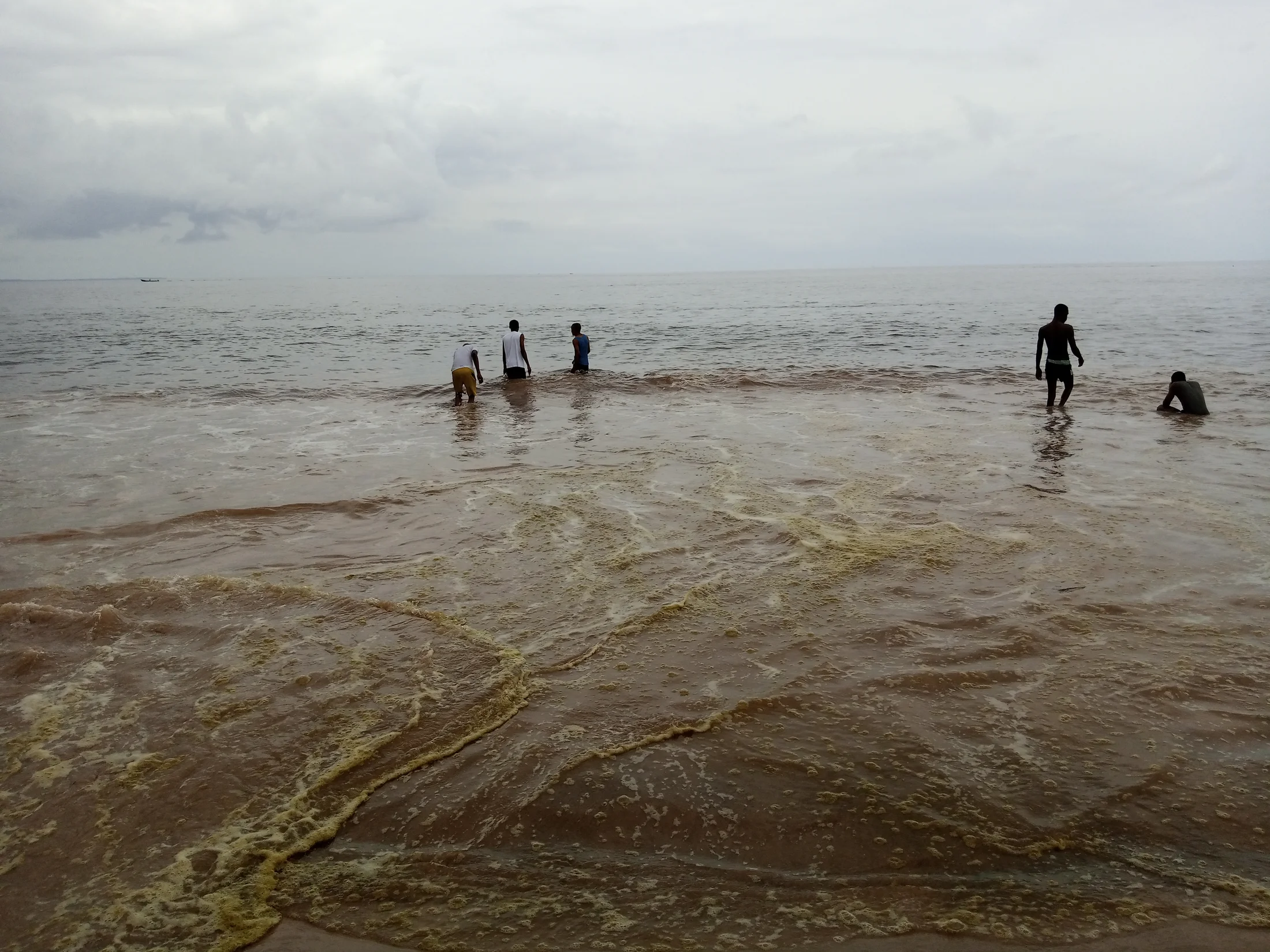 Des habitants au bord de l’océan Atlantique sur la plage de Moanda