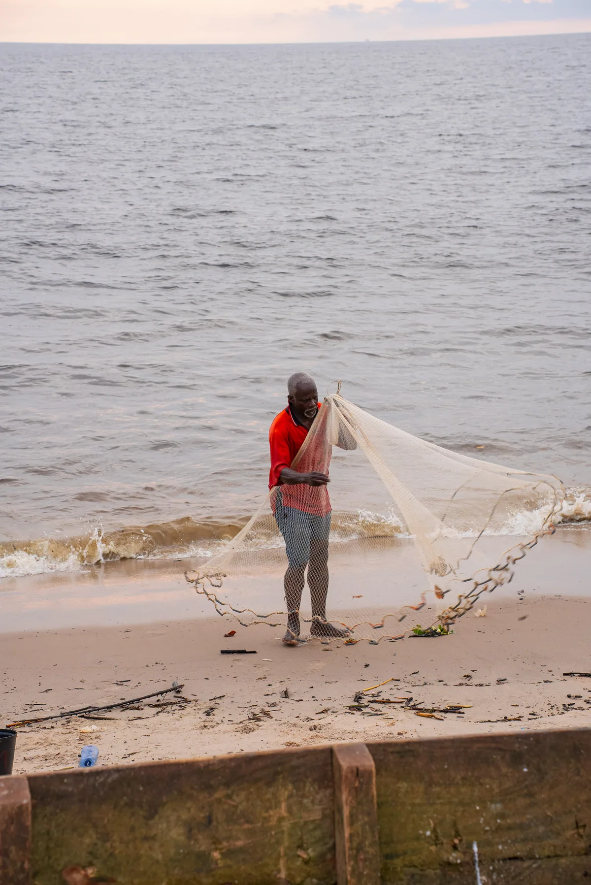 Un pêcheur prépare son filet sur le rivage
