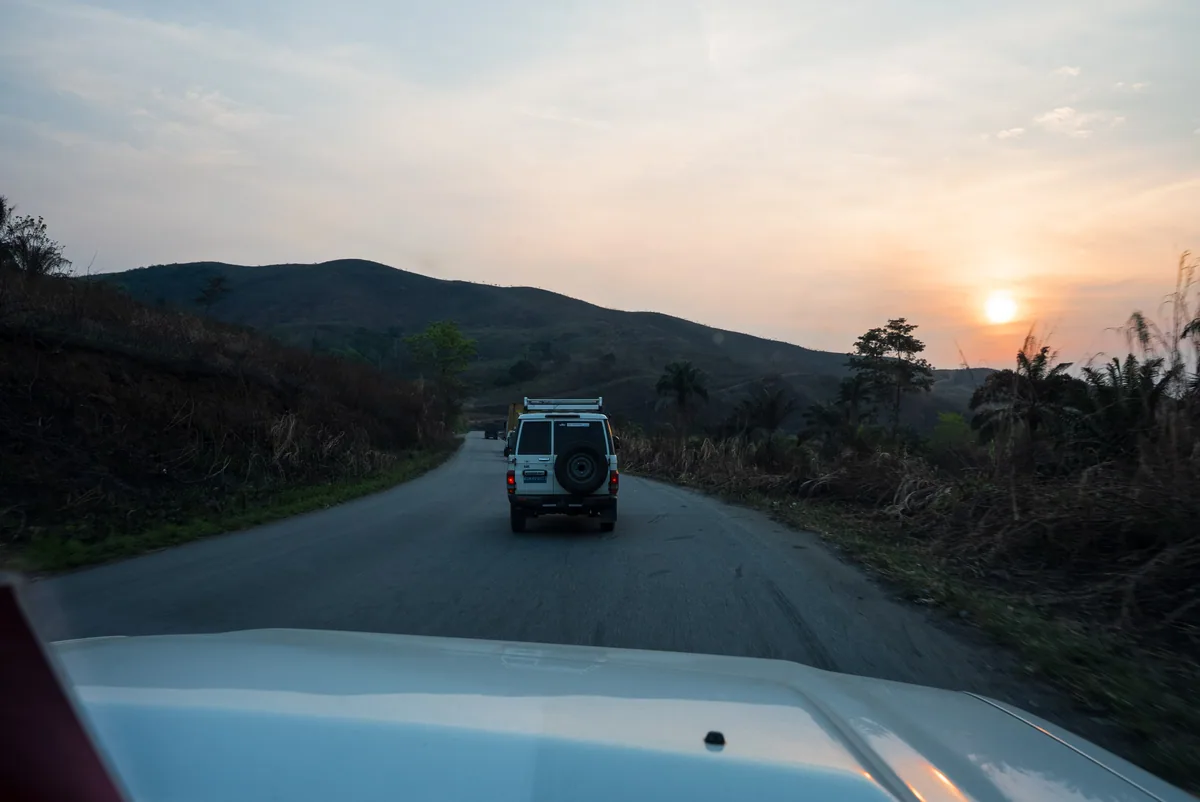 Des véhicules parcourent une route au coucher du soleil